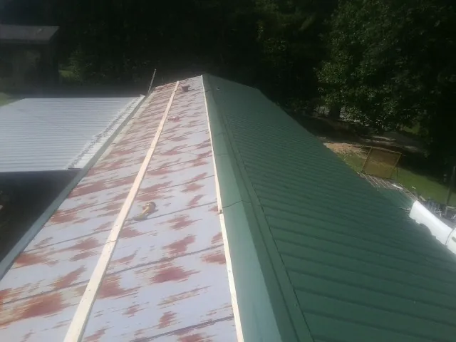 Old rusted panels beside newly installed green metal roofing — Wind Damage Roof Repair by Roofing Brothers in Mather