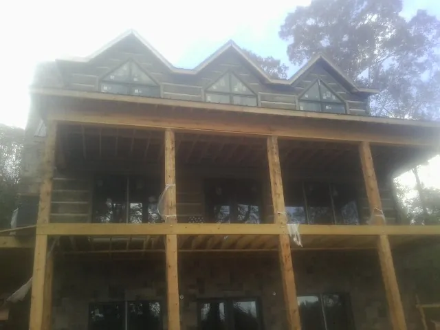 Dormers and porch framing on a large log home under construction — Roof Coating work by our crew in Mather