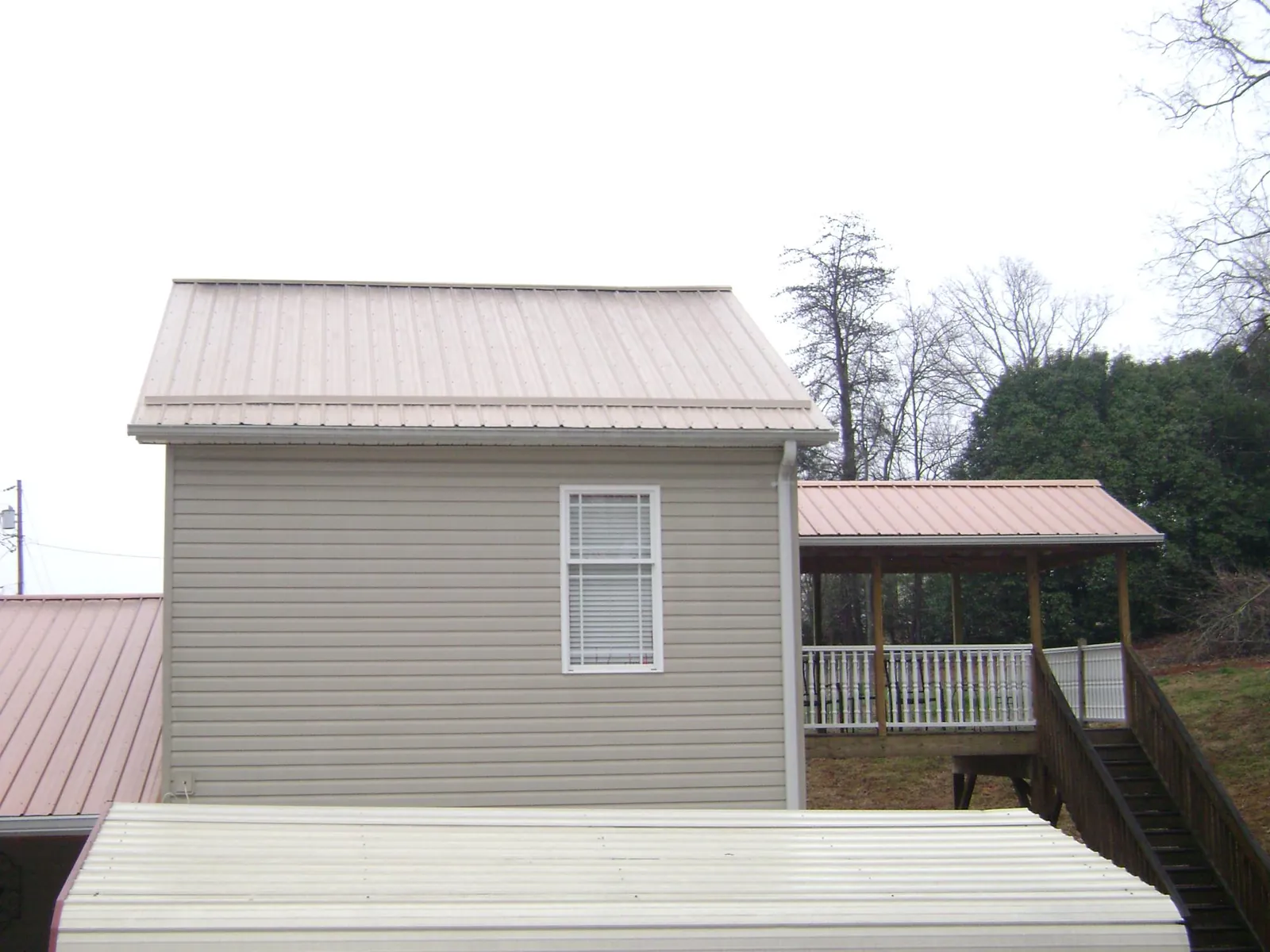 Tan metal roofs on a two story addition and attached porch, from a Roof Replacement job in Mather
